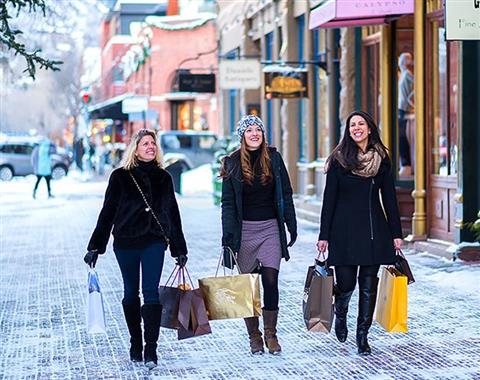 Three woman walking down a snowy road with shopping bags