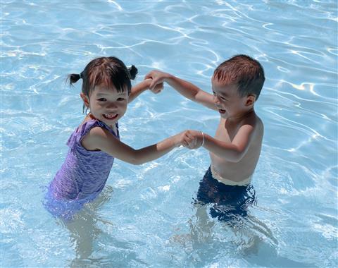 Two children holding hands in a pool together