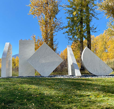 marble geometric sculpture surrounding by trees with fall leaves