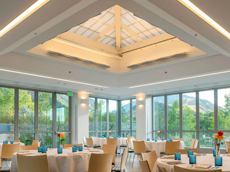 Albright Pavilion view of skylight, walls of windows to let in plenty of natural light, and round tables with fresh floral arrangements