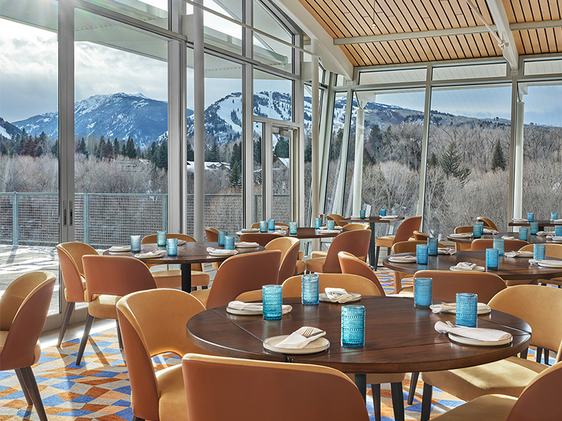 Restaurant Interior with walls of windows and square tables with wooden chairs